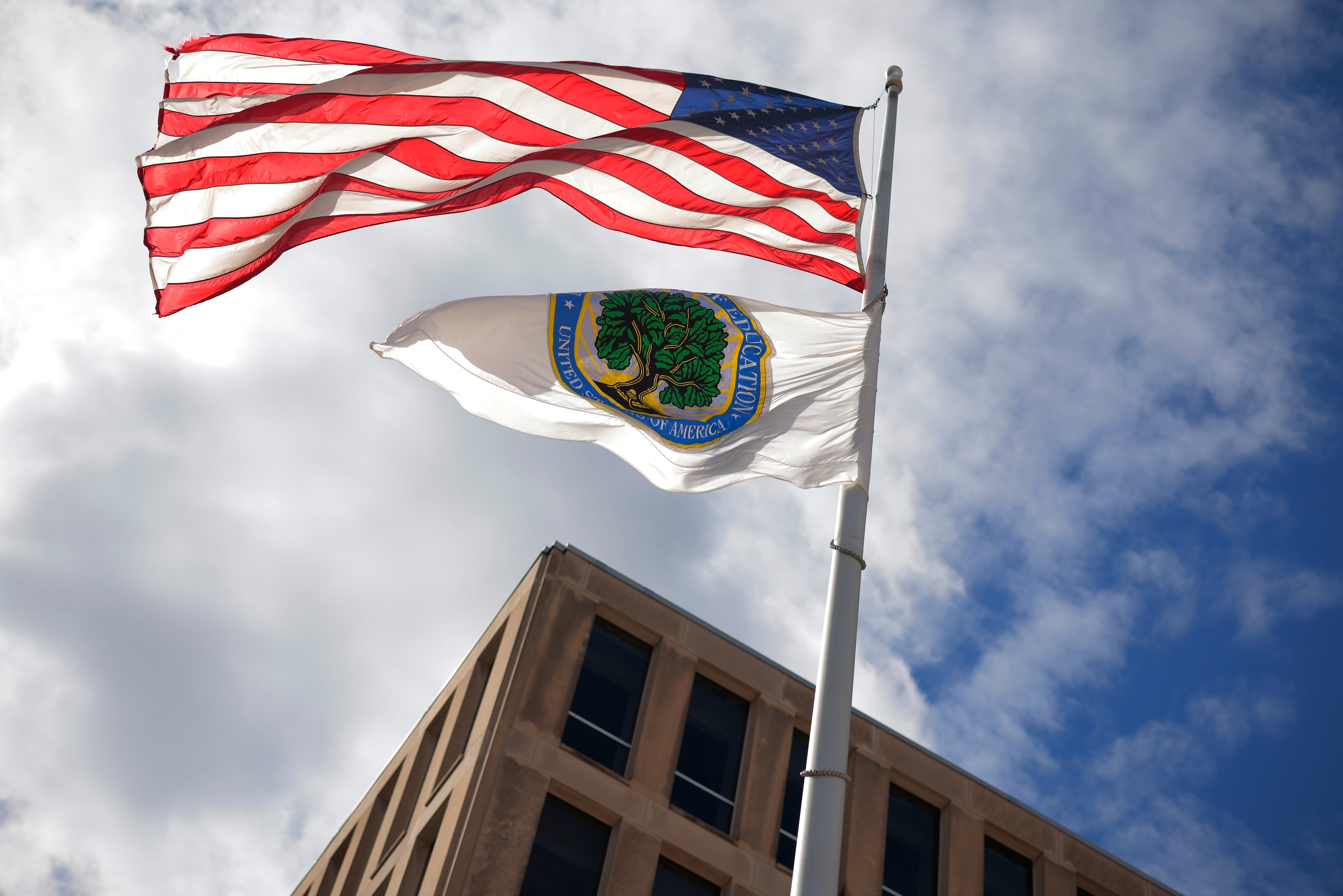 La bandera estadounidense y las banderas del Departamento de Educación ondean al viento frente a la sede del departamento el 6 de marzo de 2025 en Washington, D.C. El presidente estadounidense Donald Trump prometió durante su campaña para la Casa Blanca abolir el Departamento de Educación.