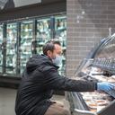 Un hombre usa mascarilla médica y guantes quirúrgicos en un esfuerzo por protegerse de contraer el coronavirus mientras compra en la tienda de comestibles