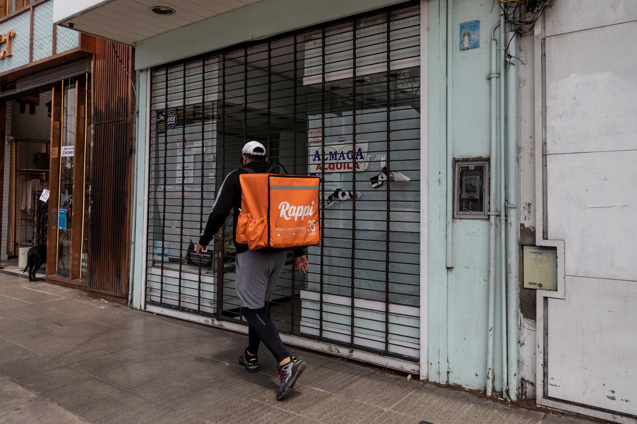 Un trabajador de reparto de Rappi Inc. pasa frente a un local comercial en alquiler en el barrio de Belgrano de Buenos Aires, Argentina, el sábado 24 de octubre de 2020. La prohibición general de despedir trabajadores durante la pandemia en Argentina parece que está acumulando más problemas que resuelve en lo que ya era uno de los peores mercados laborales del mundo.