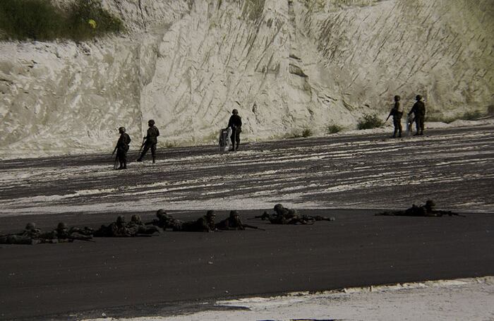 Los soldados armados apuntan sus fusiles hacia la multitud desarmada.