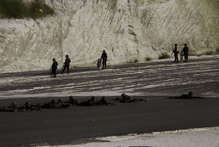 Los soldados armados apuntan sus fusiles hacia la multitud desarmada.