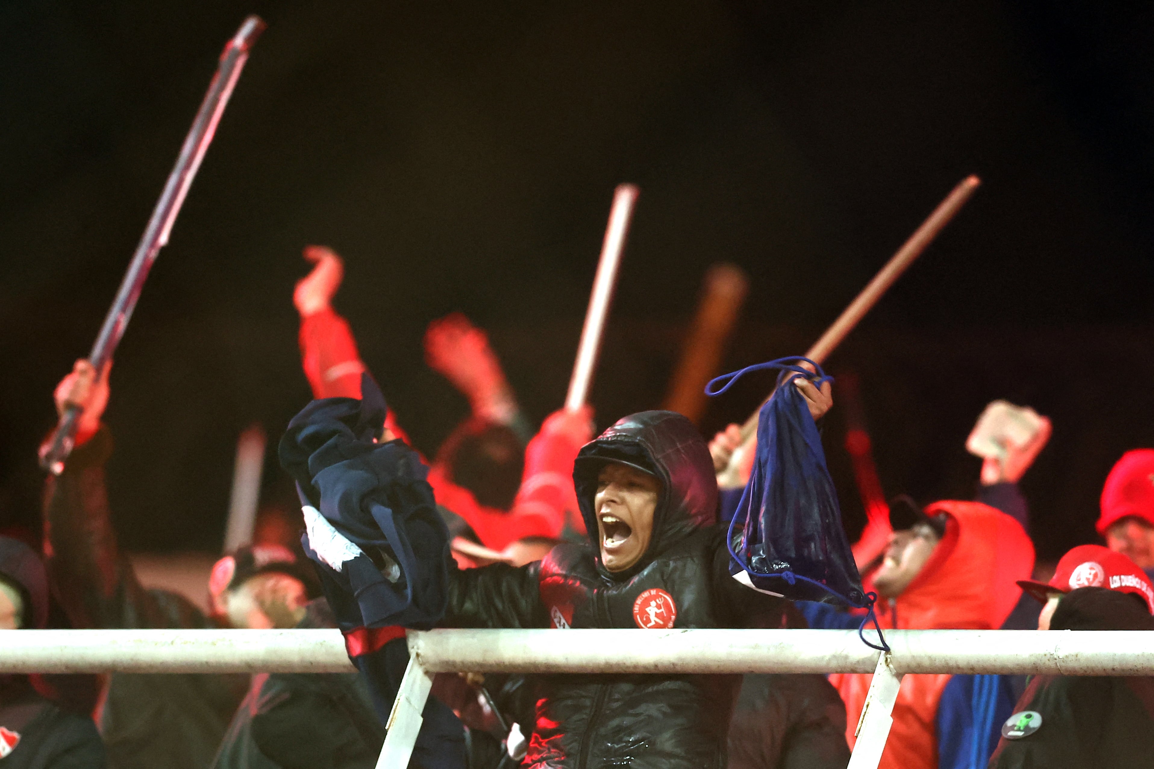 Independiente fans display stolen clothing and brandish sticks at the stands where Universidad de Chile fans were sitting during the interruption of the Copa Sudamericana round of 16 second leg football match between Argentina's Independiente and Chile's Universidad de Chile at the Libertadores de America stadium in Avellaneda, Buenos Aires province, Argentina, on August 20, 2025. The match between Independiente and Universidad de Chile was suspended due to incidents in the stands during the second half, according to the Argentine club and confirmed by Conmebol. The score was tied 1-1. (Photo by ALEJANDRO PAGNI / AFP)