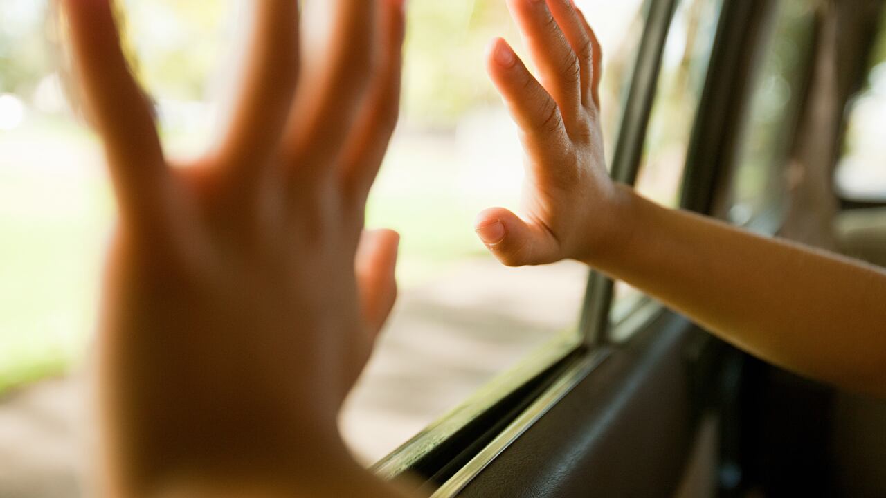 Child's hands touching car window
