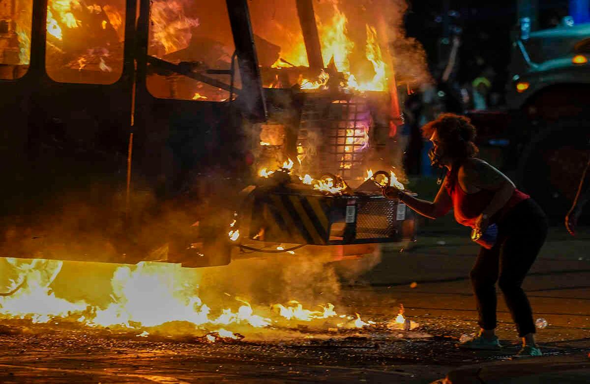Un manifestante enciende un cigarrillo en un camión de basura que se incendió durante las protestas a última hora del lunes 24 de agosto de 2020 en Kenosha, Wisconsin, provocadas por el disparo de Jacob Blake por parte de un oficial de policía de Kenosha un día antes. Foto: Morry Gash / AP 