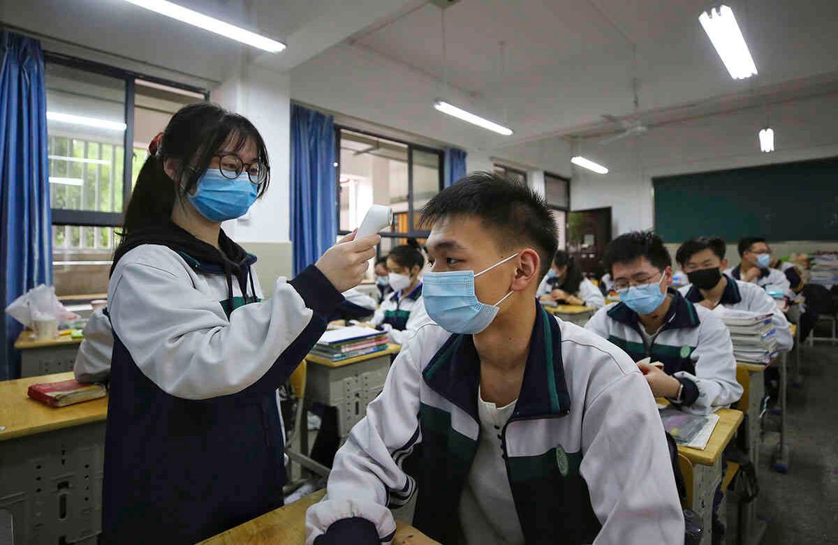 Una estudiante controla la temperatura de sus compañeros de clase en una escuela secundaria en Wuhan, en la provincia central china de Hubei, el miércoles 6 de mayo de 2020. Andy Wong / AP