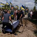 Un féretro con los restos de Roman Shadlovskyi es colocado en una fosa durante su nuevo entierro en Bucha, Ucrania, el martes 18 de julio de 2023. El veterano de las fuerzas armadas ucranianas, que fue enterrado en un principio en una fosa común como víctima no identificada tras ser asesinado el año pasad por tropas rusas, fue enterrado de nuevo el martes después de que una prueba de ADN confirmara su identidad. (AP Foto/Jae C. Hong)