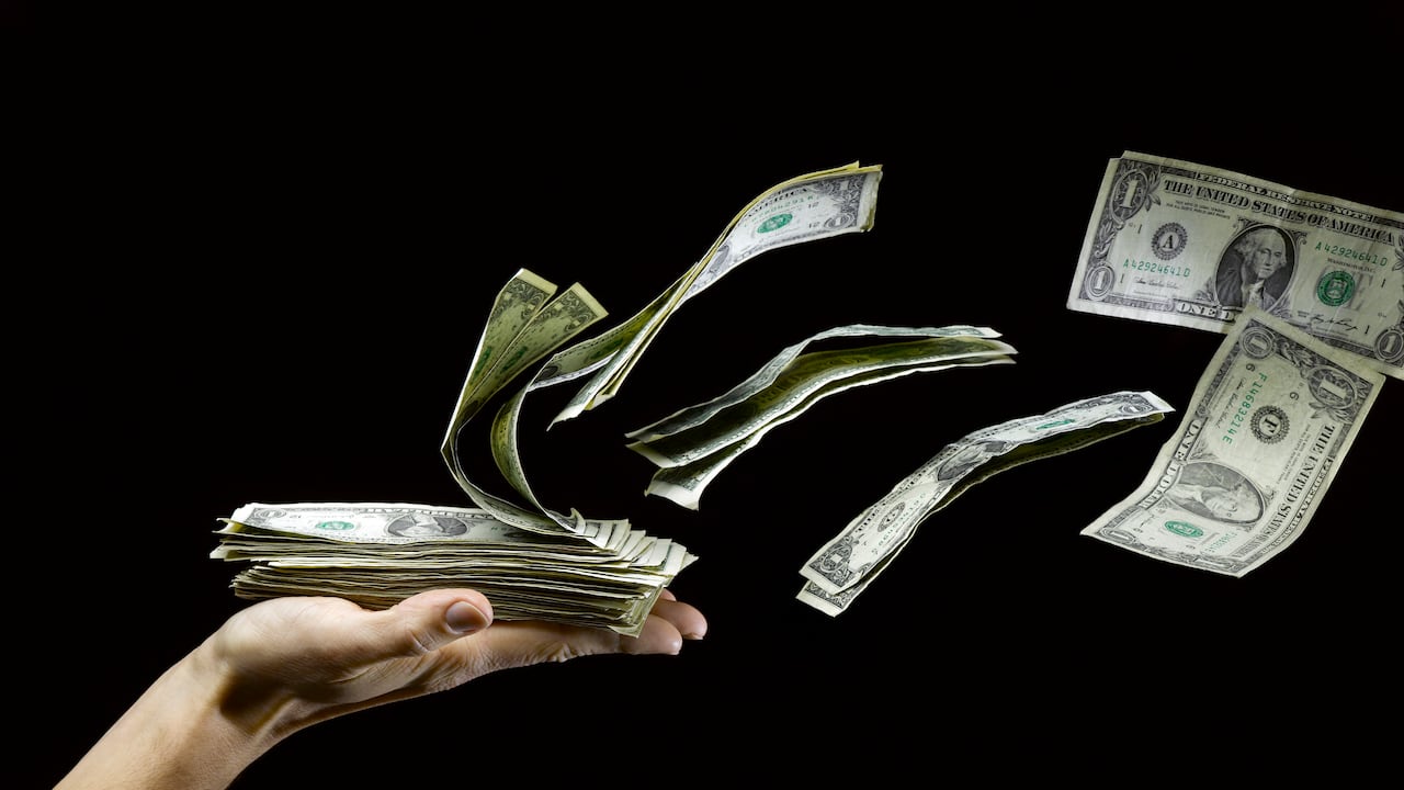 US Paper Money Flying out of Man's Hand