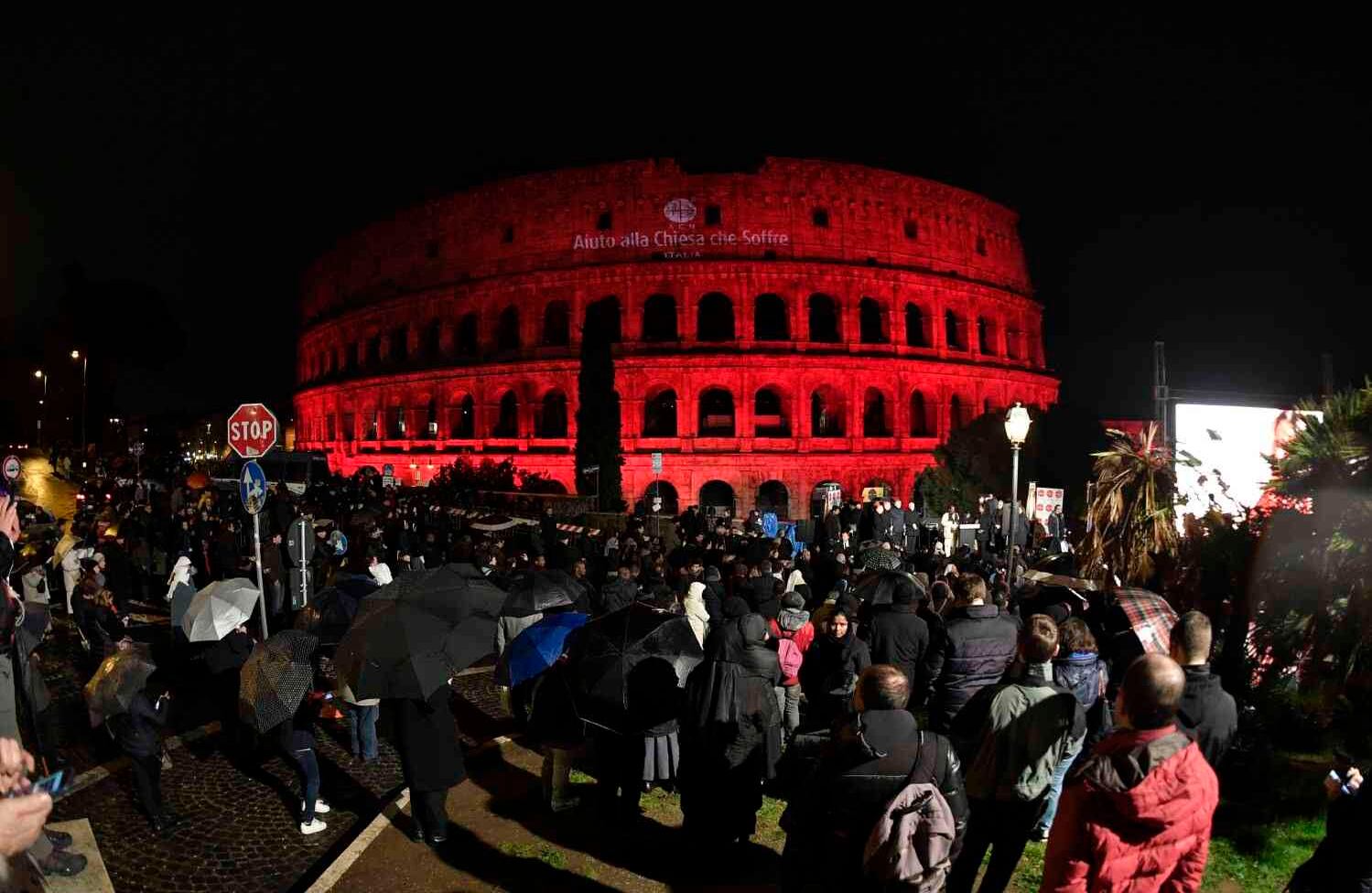 La gente se reúne para una ceremonia afuera del Coliseo Romano, iluminada en luz roja y leyendo "Ayuda a la Iglesia que Sufre", llamando la atención sobre la persecución de cristianos en todo el mundo, particularmente en Siria e Irak, el 24 de febrero de 2018 en Roma . Andreas SOLARO / AFP