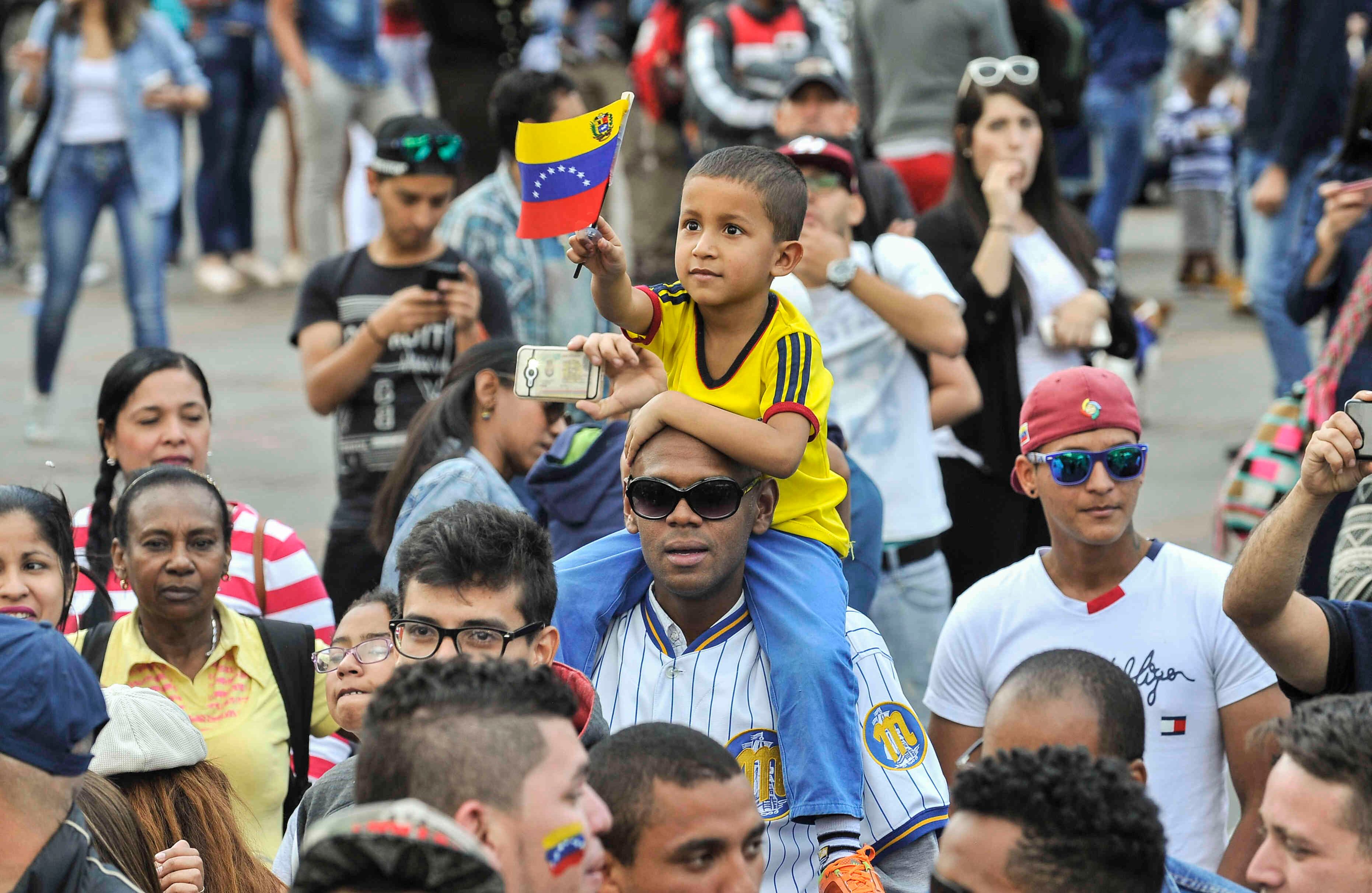 Un ciudadano venezolano carga a un niño mientras hace fila para sufragar, en la Plaza de Bolívar, en Bogotá, Colombia,  el domingo 16 de julio de 2017, durante las votaciones al plebiscito. Esta jornada democrática ha sido  impulsada  por la oposición al gobierno de Nicolás Maduro. En las tarjetas, los ciudadanos deben responder ‘sí’ o ‘no’ a tres preguntas: la primera es si respalda el plan del presidente Nicolás Maduro de cambiar la Constitución; la segunda es si  apoya la intervención de las Fuerzas Armadas para “restituir el orden constitucional” y por último si desea un gobierno de unidad nacional. Foto: Carlos Julio Martínez / SEMANA