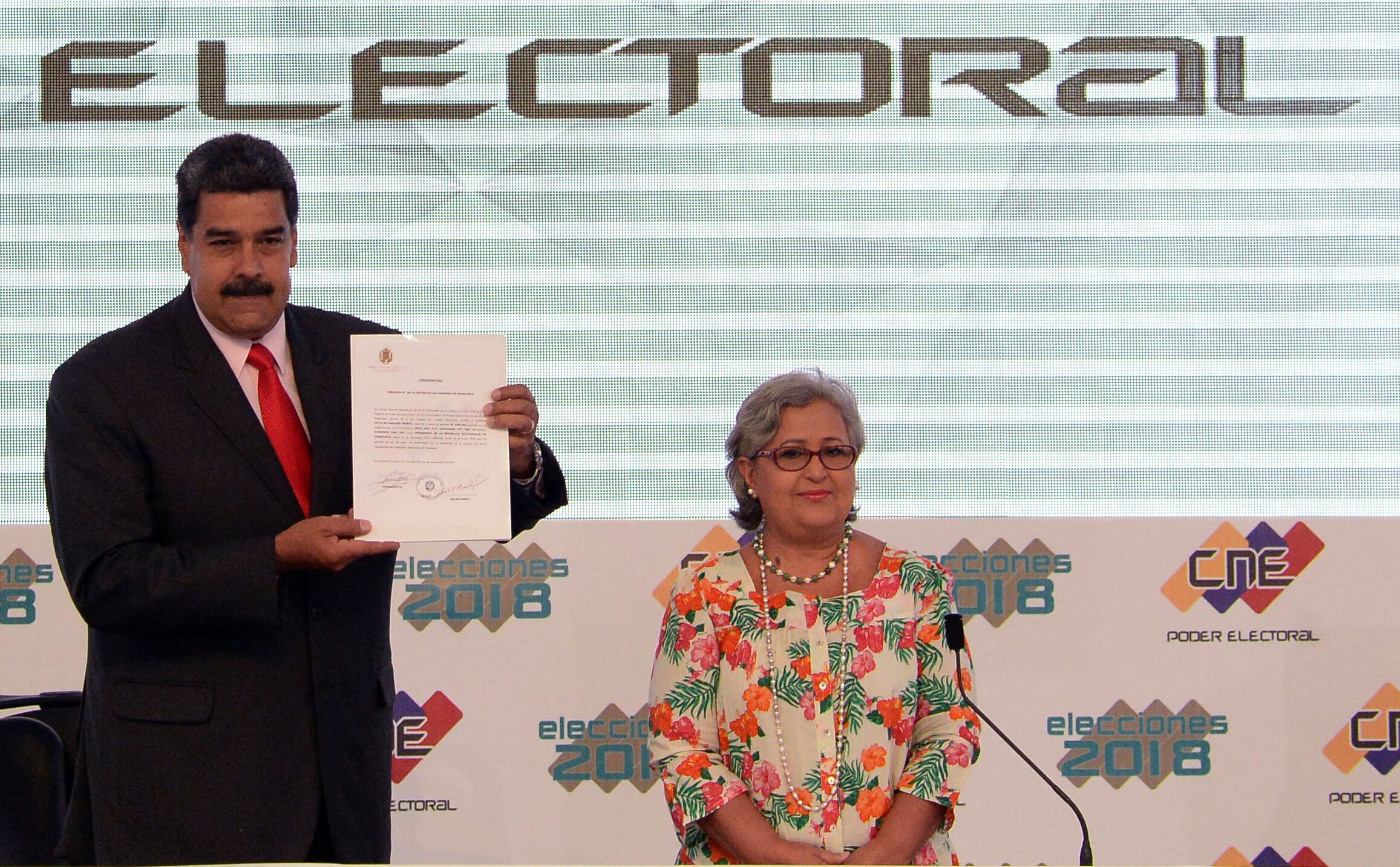 El presidente venezolano, Nicolás Maduro (izq.), muestra el documento emitido por el Consejo Nacional Electoral (CNE) que lo proclama reelegido para el período 2019-2025, junto a la presidenta del CNE, Tibisay Lucena, en la sede del CNE en Caracas el 22 de mayo de 2018.