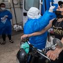 (FILES) In this file photo taken on December 18, 2020 a man on a motorcycle undergoes a PCR test for COVID-19 at a testing facility set up in front of the Uruguayan Congress in Montevideo, amid the novel coronavirus pandemic. - With the highest COVID-19 contagion rate in the world, which became the main death reason, Uruguay goes through the worst moment of the pandemic, months after being erected as a success example in the control of the health emergency. (Photo by Pablo PORCIUNCULA / AFP)
