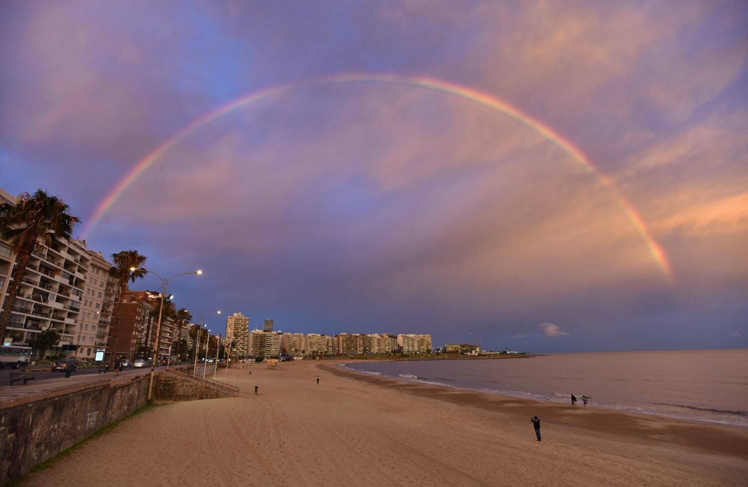 Vista de un arcoiris durante la puesta de sol sobre la playa de Pocitos, en Montevideo el 5 de enero de 2018. / AFP PHOTO / Mariana SUAREZ