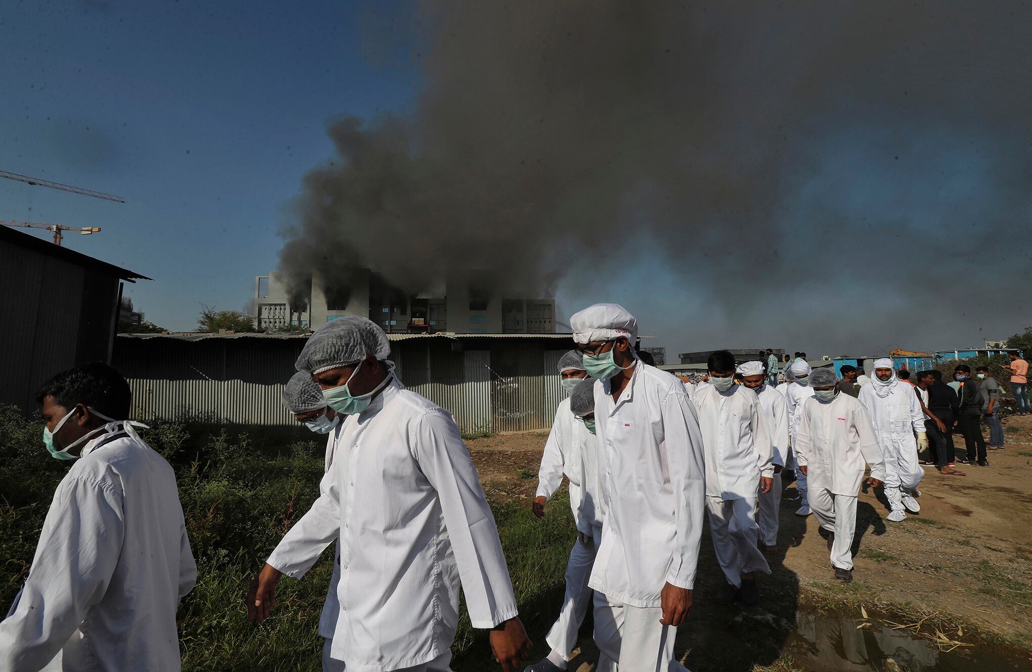 Los empleados se van mientras sale humo de un incendio en el Serum Institute of India, el mayor fabricante de vacunas del mundo que fabrica la vacuna AstraZeneca / Oxford University para el coronavirus, en Pune, India, el jueves 21 de enero de 2021 (AP Photo / Rafiq). Maqbool)