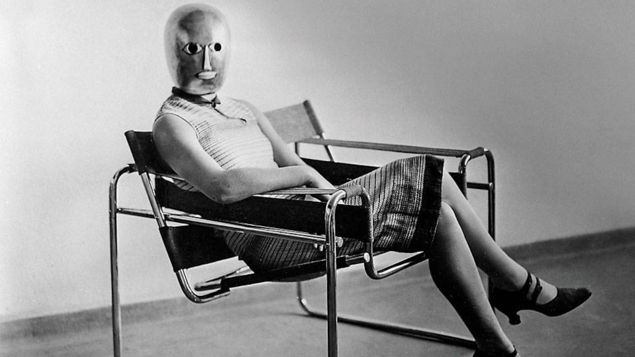 Estudiante de la Bauhuaus sentada en la silla Wassily, de Marcel Breuer, con máscara de Oskar Schlemmer