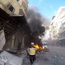 In this photo provided by the Syrian Civil Defense White Helmets, a Syrian White Helmet civil defense worker runs at the site where a shell struck in the outskirts of the northern town of Jisr al-Shoughour, west of the city of Idlib, Syria, Thursday, Oct. 5, 2023. A drone attack struck a packed graduation ceremony for military officers in the Syrian city of Homs on Thursday, killing and wounding dozens reports said. Following the drone attack, the government shelled villages in Idlib province, in the rebel-held northwestern part of the country. (Syrian Civil Defense White Helmets via AP)