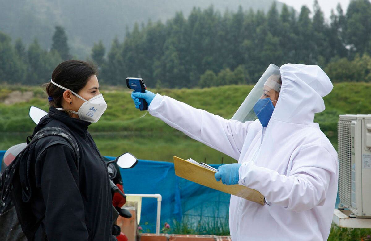 En las afueras de la obra, los empleados hacen una fila en la que guardan más de un metro de distancia, mientras una persona, cubierta por un traje de seguridad, les pone en la frente el escáner para detectar si tienen fiebre. 