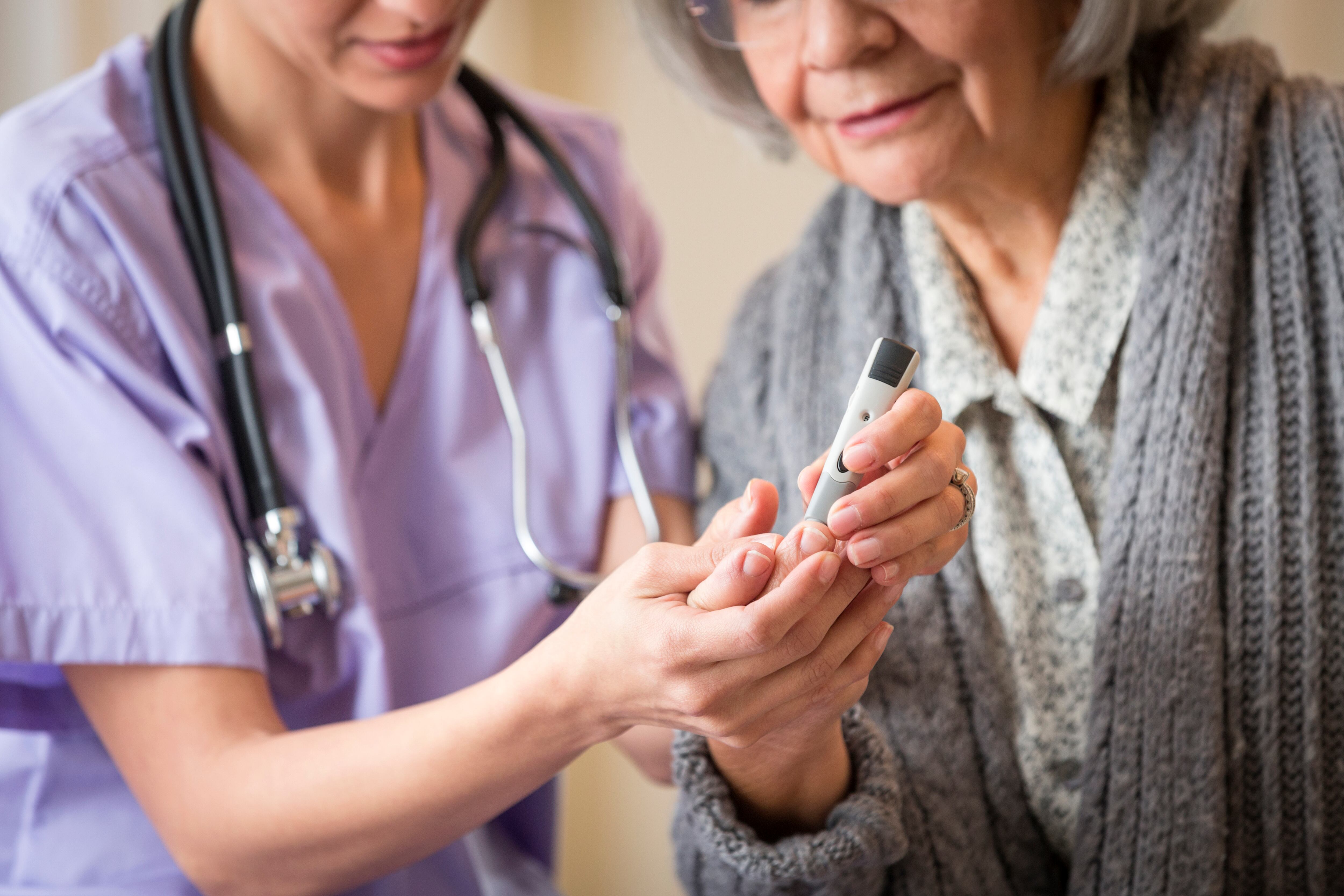 Nurse giving blood sugar test to patient in home