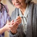 Nurse giving blood sugar test to patient in home