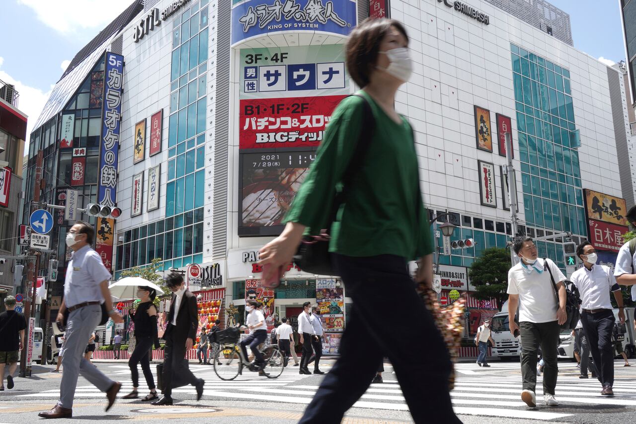 Gente caminando por un cruce cerca de la estación de tren de Shimbashi en Tokio, el jueves 29 de julio de 2021, al día siguiente de que se batiera un récord de contagios del virus en la ciudad anfitriona de los Juegos Olímpicos. (AP Foto/Kantaro Komiya)
