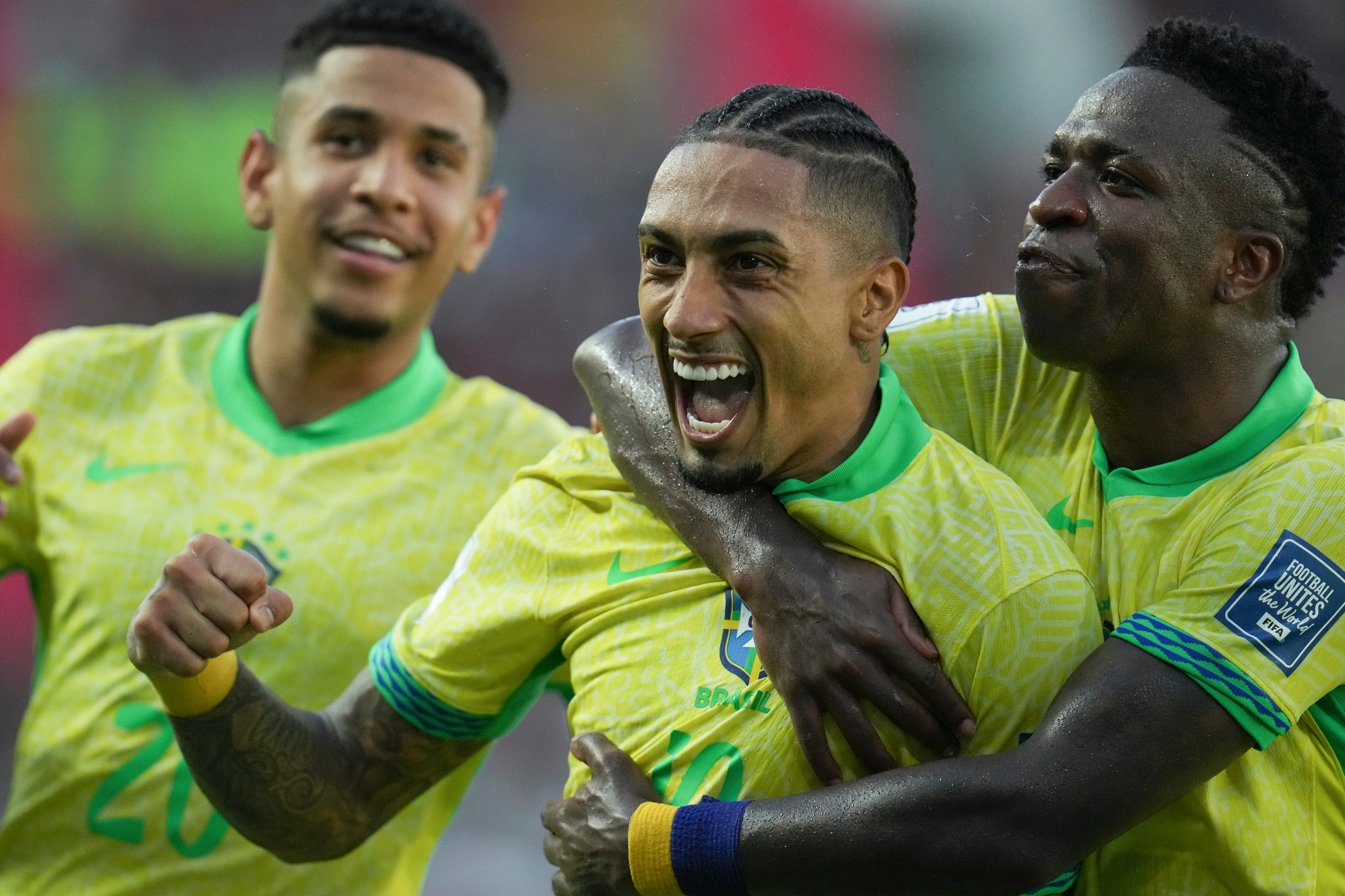 El brasileño Raphinha, en el centro, celebra con su compañero de selección Vinicius Junior, a la derecha, tras anotar el primer gol de su equipo contra Venezuela durante un partido de clasificación para la Copa Mundial de la FIFA 2026 en el estadio Monumental de Maturín, Venezuela, el jueves 14 de noviembre de 2024. (Foto AP/Ariana Cubillos)