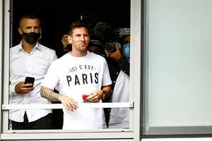Argentinian football player Lionel Messi salutes supporters from a window after he landed on August 10, 2021 at Le Bourget airport, north of Paris, to become Paris Saint-Germain's new player following his departure from Barcelona, the club he has represented for the entirety of his 17-year professional career so far. - Asked by reporters at Barcelona's El Prat airport if the Argentine star would later on sign with the French club, Jorge Messi, the father and player's agent, said: "Yes". (Photo by Sameer Al-DOUMY / AFP)