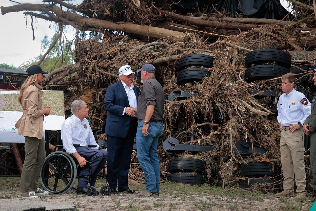 KERRVILLE, TEXAS - JULY 11: President Donald Trump, first lady Melania Trump and Texas Governor Greg Abbott meet with local emergency services personnel as they survey flood damage along the Guadalupe River on July 11, 2025 in Kerrville, Texas. Trump traveled to Texas one week after flash flooding along the Guadalupe River swept through cities, mobile home parks and summer camps, killing 120 people. Ninety-six of those killed were in Kerr County, where the toll includes at least 36 children. (Photo by Chip Somodevilla/Getty Images)