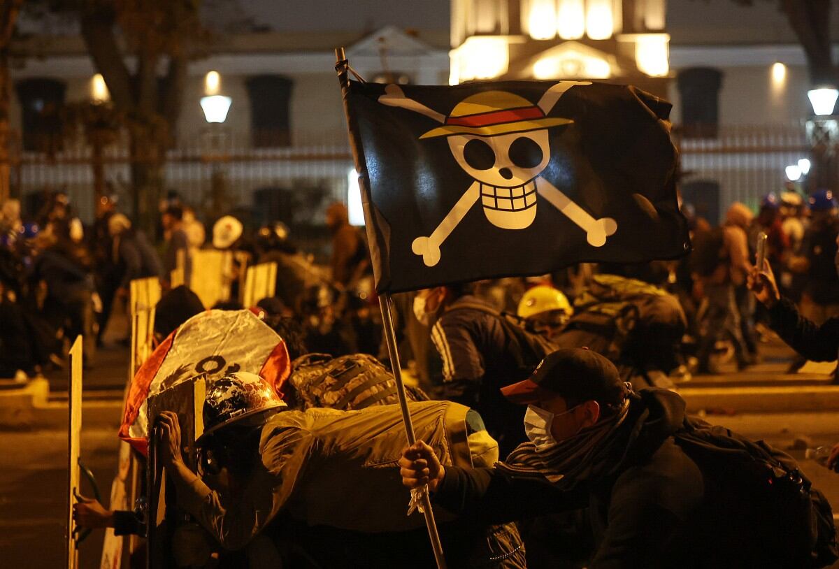 Manifestantes con una bandera del manga "One Piece" se enfrentan a agentes de la policía antidisturbios durante una protesta contra el presidente interino de Perú, José Jeri, en Lima el 15 de octubre de 2025. (Foto de Hugo Curotto / AFP)
