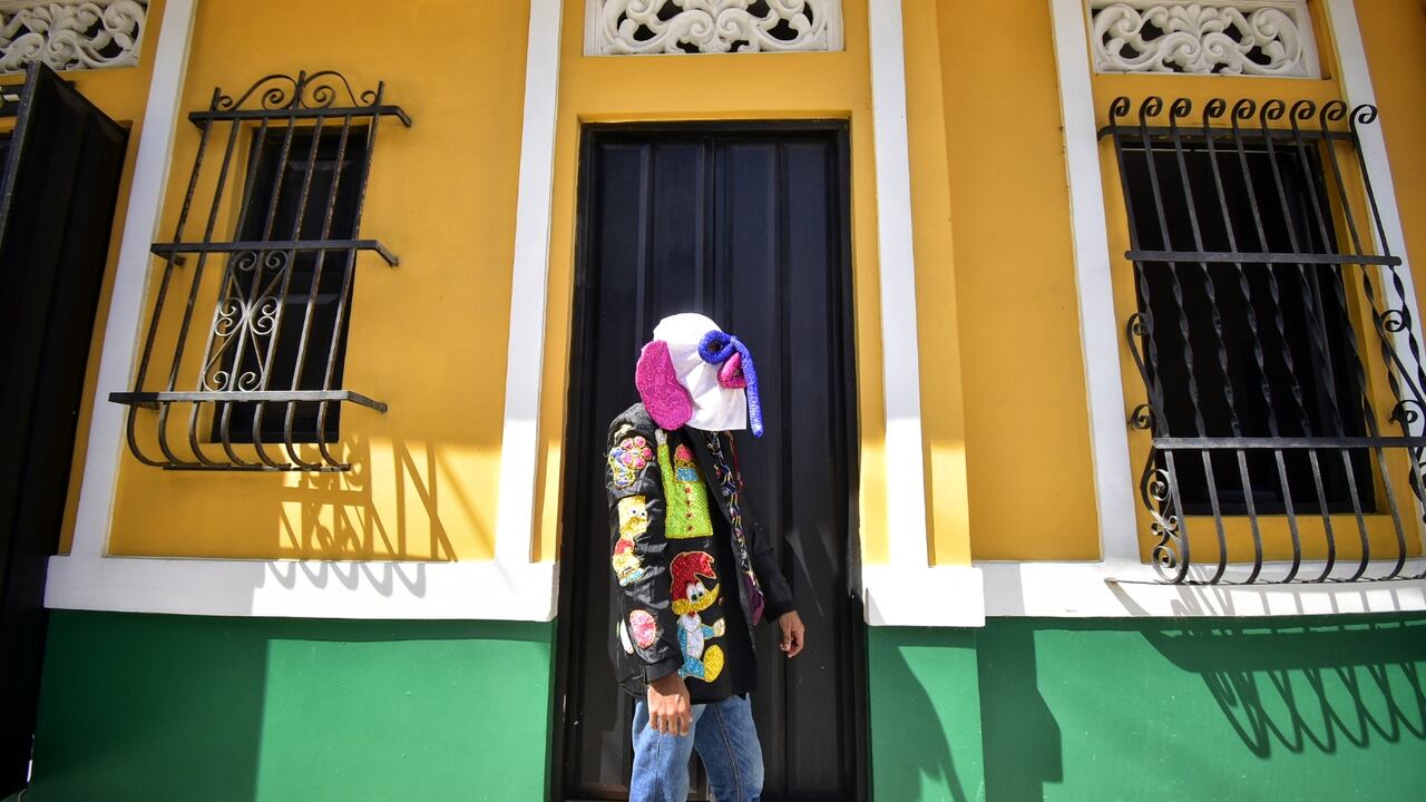 Un disfraz de marimonda camina frente a una tradicional casa del Barrio Abajo.