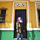 Un disfraz de marimonda camina frente a una tradicional casa del Barrio Abajo.