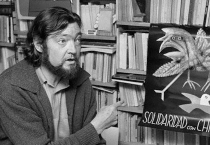 Julio Cortázar en su apartamento en el barrio Montparnasse, en París, señala un afiche de solidaridad con Chile en 1974, un año después del golpe de Estado de Augusto Pinochet