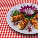 Chicken kebab with onion adn green vegetables on checked tablecloth
