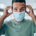 Apuesto joven poniéndose una máscara protectora para la prevención contra virus.