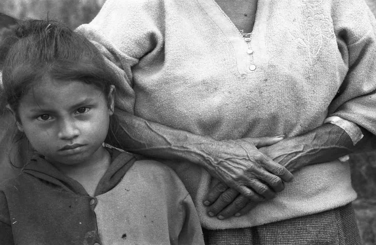 La mujer observa uno de los cuerpos envueltos en plástico y colgado de una guadua que llevan varios campesinos por la plaza del municipio de Peque, Antioquia en julio del año 2001. “Hace 50 años viví esta misma tragedia y perdimos las cosechas de maíz y fríjol y nos robaron muchos animales. Hoy la estoy repitiendo con mis hijos y nietos. ¿Hasta Cuándo?”.