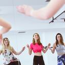 Group of Cute Smiling Females Training Zumba in front of the Mirror in Gym