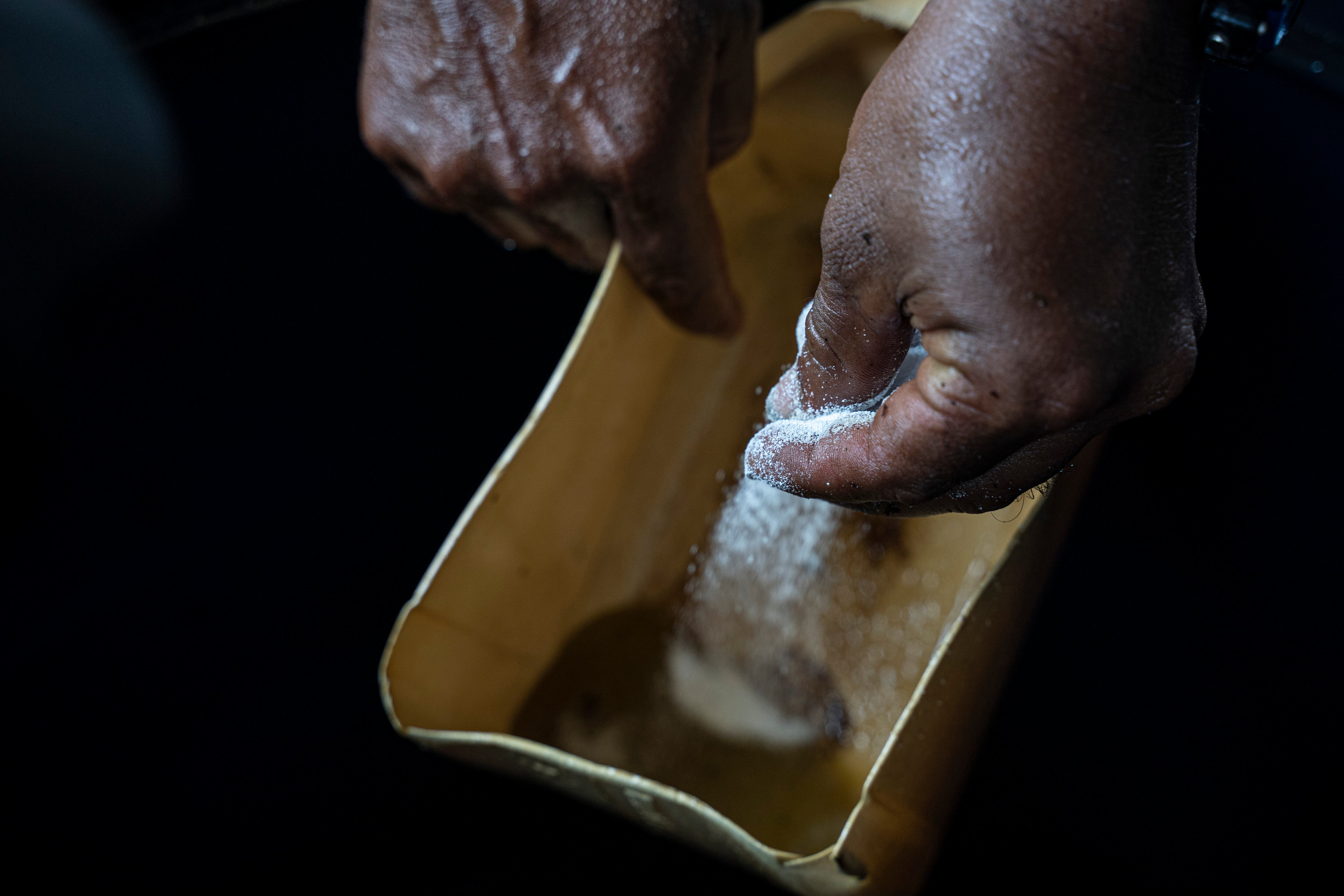 Un trabajador rocía soda caucásica sobre agua con alcaloide de coca en un "laboratorio" donde las hojas de coca se procesan en pasta de coca