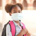 Back to school. African descent girl on school campus. She wears a mask for COVID-19, Coronavirus protection.