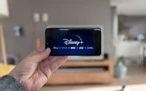 Pantalla de inicio de Disney+ en el teléfono móvil. Disney+ video en línea, servicio de suscripción de transmisión de contenido. El hombre levanta su teléfono inteligente y mira disney plus