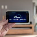 Pantalla de inicio de Disney+ en el teléfono móvil. Disney+ video en línea, servicio de suscripción de transmisión de contenido. El hombre levanta su teléfono inteligente y mira disney plus