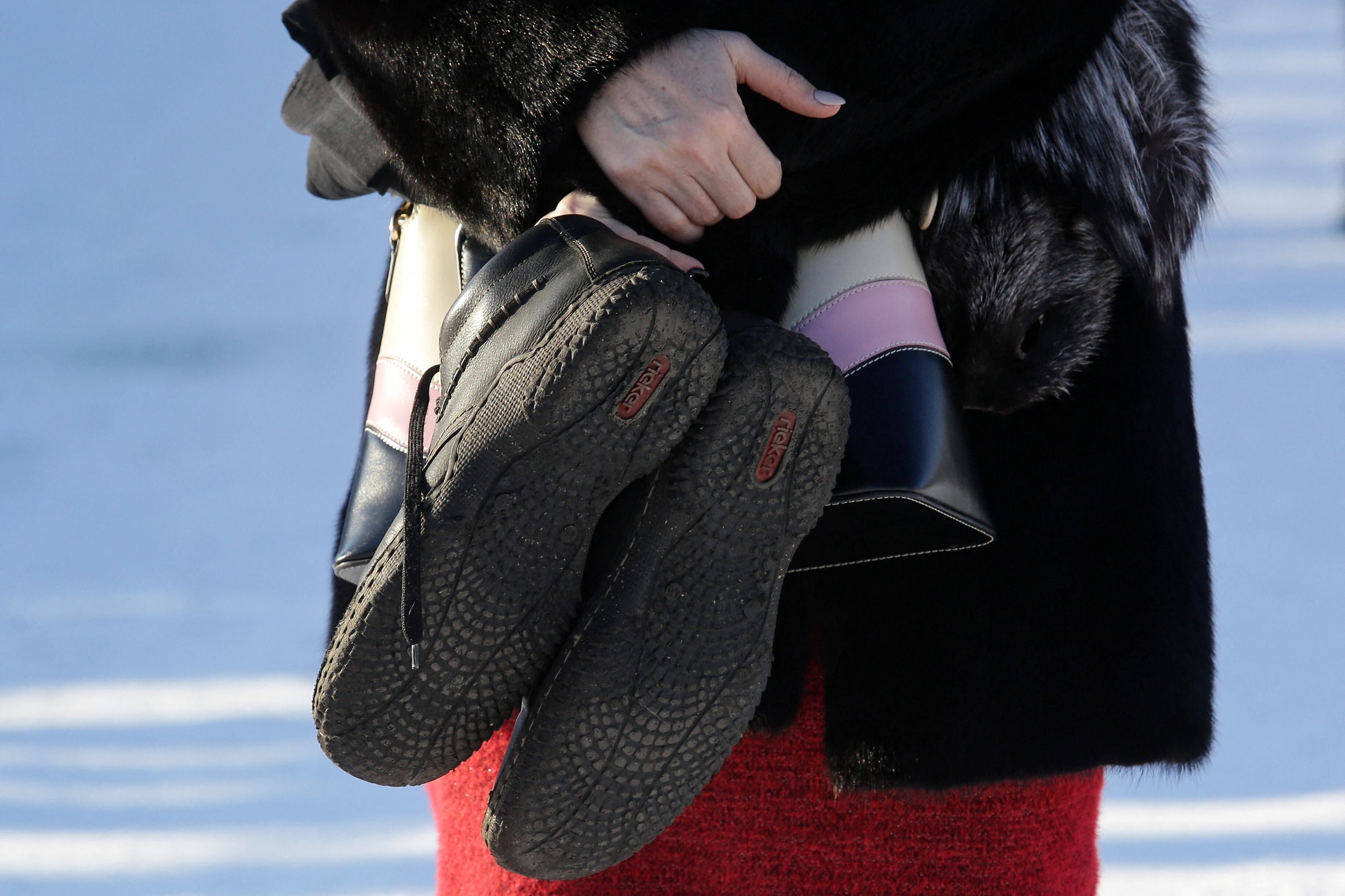 Una mujer sosteniendo un par de zapatos de hombre se encuentra cerca de la mina de carbón de Listvyazhnaya, cerca de la ciudad de Belovo en la región de Kemerovo, el 26 de noviembre de 2021. - Se informó que más de 50 personas murieron el 25 de noviembre después de que el humo llenara un carbón siberiano. la mía y un esfuerzo de rescate terminó en tragedia. (Foto de Rostislav NETISOV / AFP)