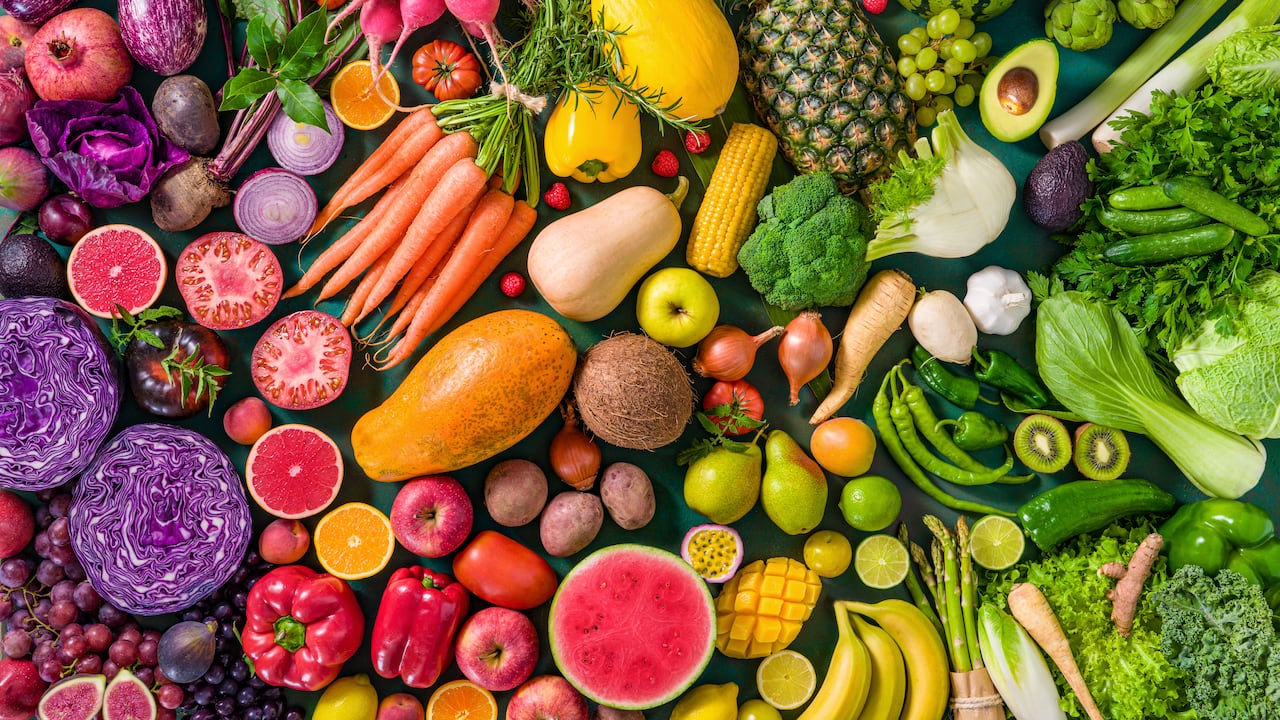 Comida vegana variada con frutas y verduras crudas de colores.