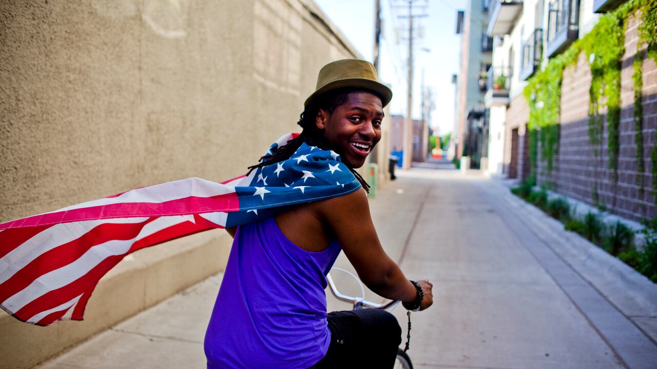 Un joven con una bandera estadounidense alrededor del cuello.