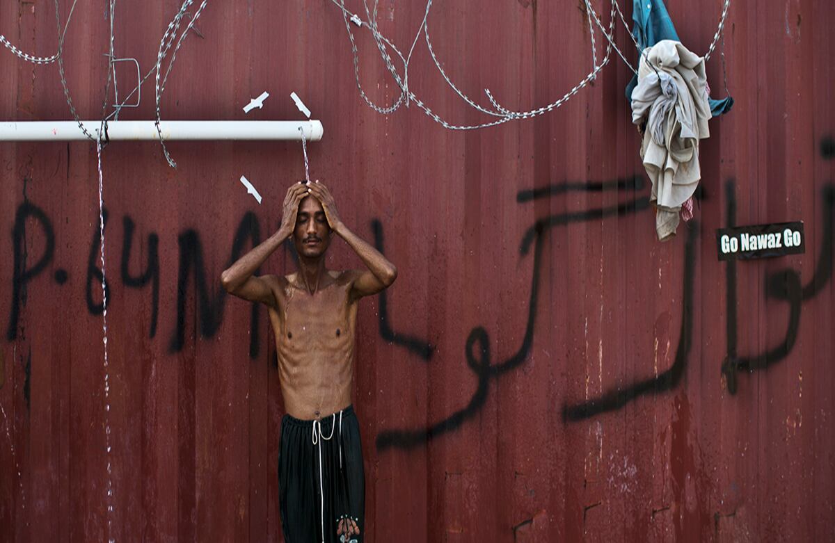 Uno de los protestantes en contra del gobierno toma una ducha donde él y otros están acampando desde mediados de agosto en señal de inconformidad con la elección del Primer Ministro paquistaní Nawaz Sharif. (AP)