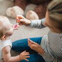 Un bebé bebe un poco de medicina de una cuchara que su madre le está alimentando en su casa.