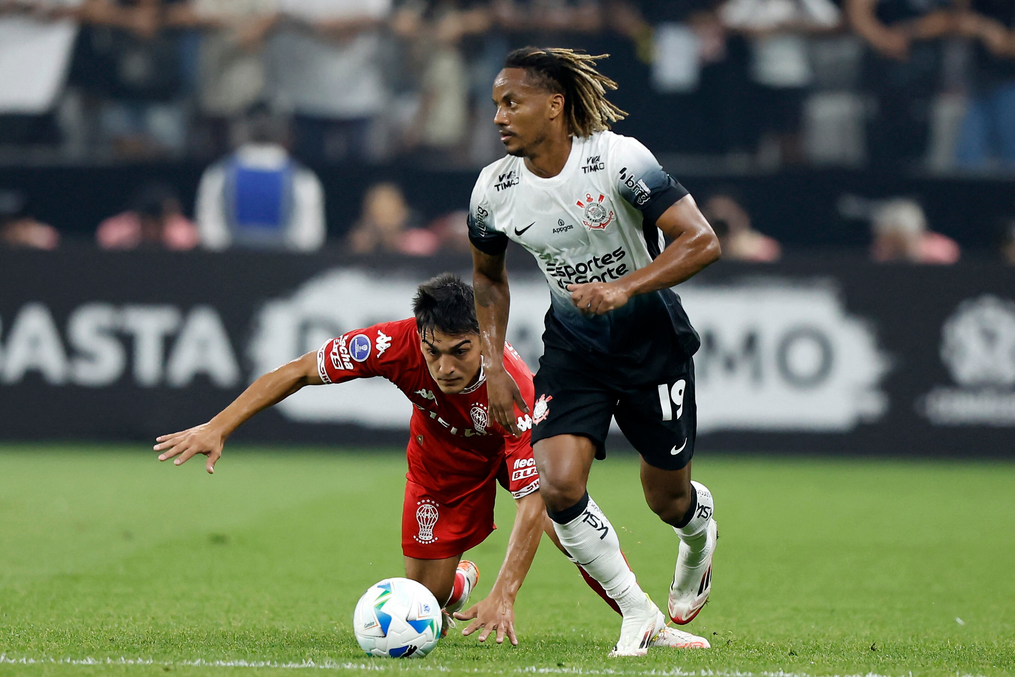 El defensor #25 de Huracán, César Ibáñez (izq.) y el delantero peruano #19 de Corinthians, André Carrillo, luchan por el balón durante el partido de fútbol de la fase de grupos de la Copa Sudamericana.