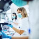 Small group of female laboratory assistants checking blood, using microscope and doing test for bacteria.