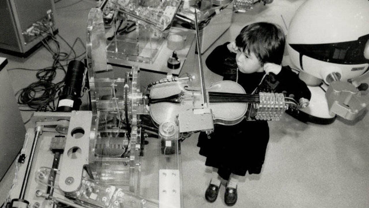 Mariko Macksey de cuatro años escucha a un robot tocar el violín en el Centro de Ciencia de Ontario en 1989.