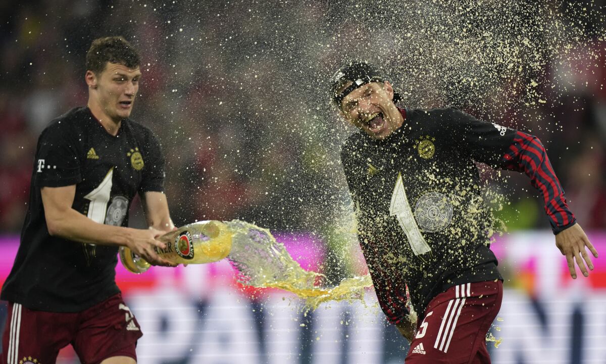 Bayern's Benjamin Pavard, left, and Bayern's Thomas Mueller celebrate at the end of the German Bundesliga soccer match between Bayern Munich and Borussia Dortmund, at the Allianz Arena, in Munich, Germany, Saturday, April 23, 2022. (AP/Matthias Schrader)