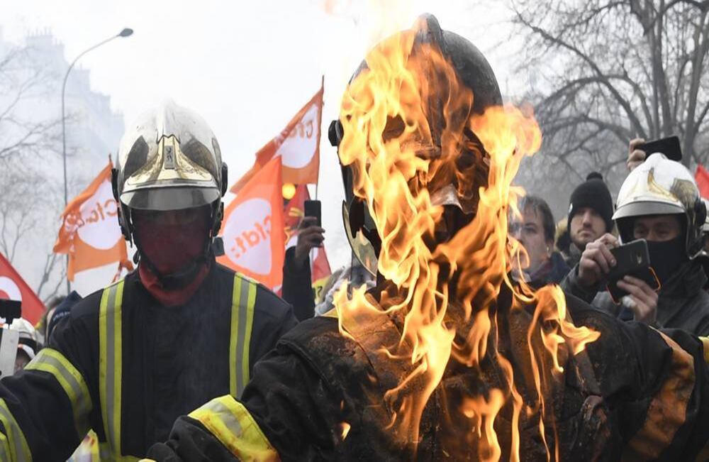 Un bombero enciende a otro en llamas, mientras participan en una manifestación en contra del plan de gobierno francés de jubilación del país, en París, el 28 de enero de 2020. Foto: Bertrand Guay/ AFP.