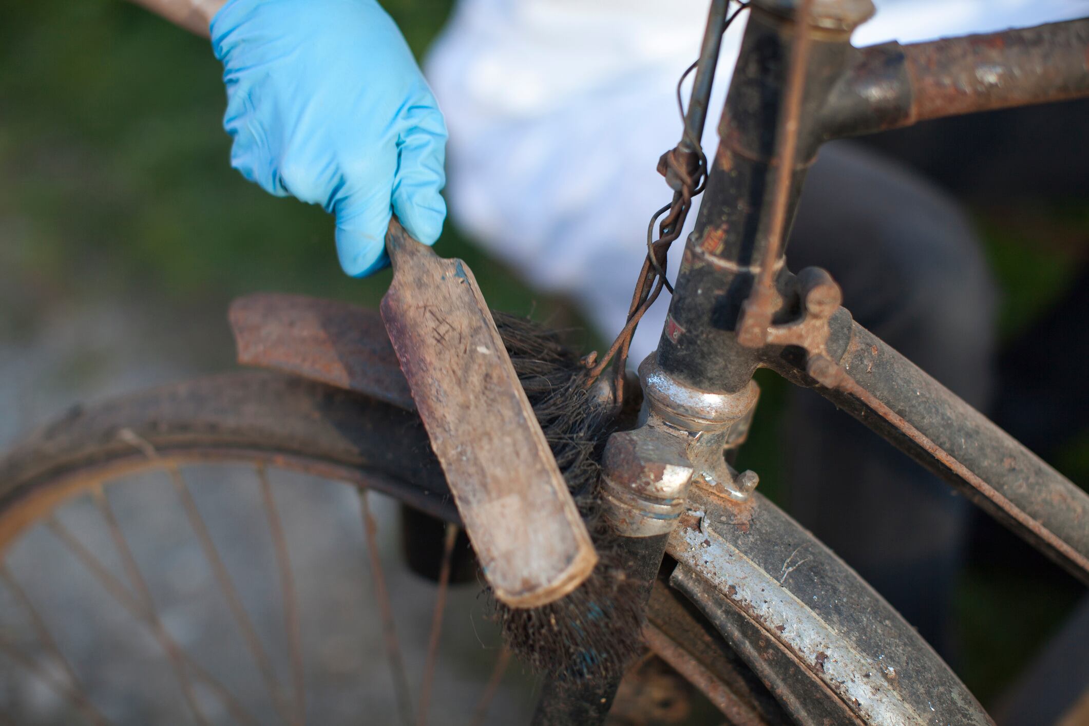 Young restorer woman cleaning dust from vintage bicycle.