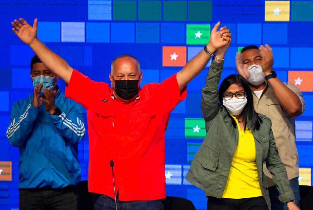 Diosdado Cabello, from The United Socialist Party of Venezuela (PSUV) and Great Patriotic Pole Alliance, left, raises his arm with Venezuela's Vice President Delcy Rodriguez as they celebrate their party's victory in the country's parliamentary elections in Caracas, Venezuela, Monday, Dec. 7, 2020. (AP Photo/Ariana Cubillos)